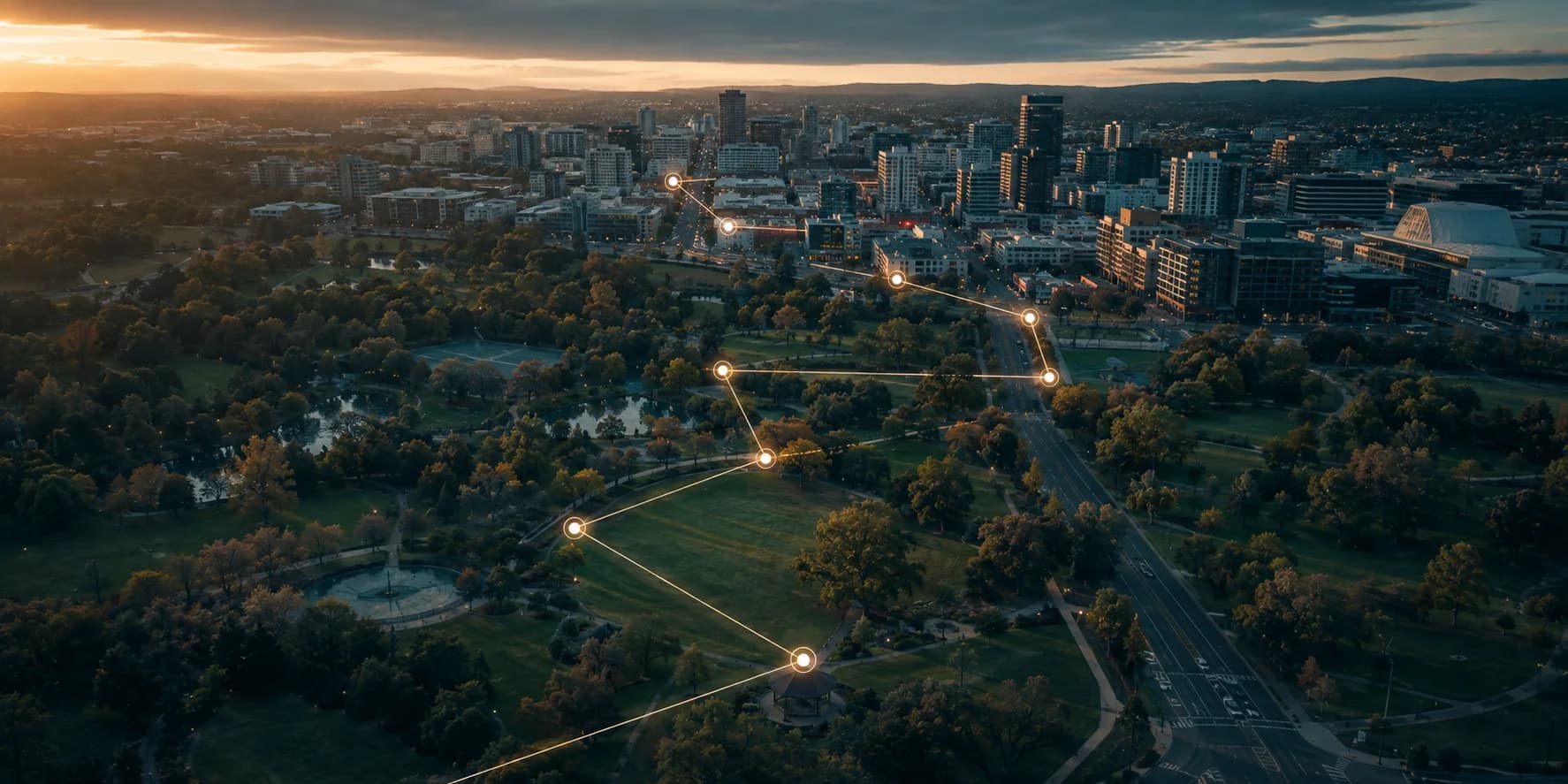 Aerial view of a city at sunset with points of light linked into a trail